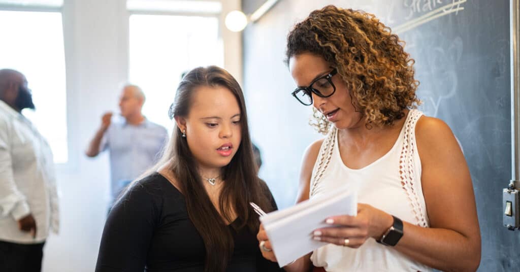 One woman explaining something on a notepad to another woman