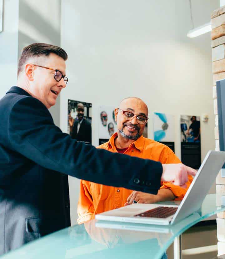 Two people look at a laptop together while smiling.