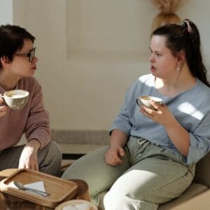 Two people are having a conversation over coffee in an office setting. The person on the left is listening intently to the person on the right. Active listening is an important part of the solution-focused approach to supported employment.