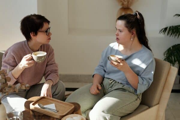 Deux personnes discutent autour d'un café dans un bureau. La personne de gauche écoute attentivement la personne de droite. L'écoute active est un élément important de l'approche de l'emploi assisté axée sur les solutions.