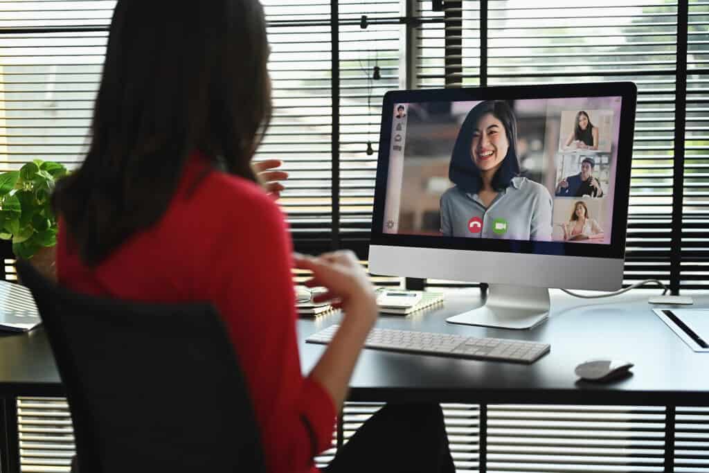Back view of female entrepreneur having video call with colleague on the computer.