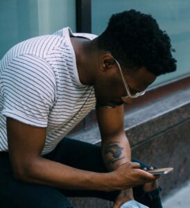 Photo: Man sitting outside holding a cell phone