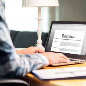 A person is using a laptop to view and edit their resume. Learning how to write and edit a resume using applications like Microsoft Word or Google Docs is a critical digital literacy skill.