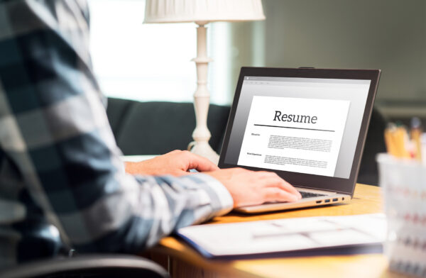 A person is using a laptop to view and edit their resume. Learning how to write and edit a resume using applications like Microsoft Word or Google Docs is a critical digital literacy skill.