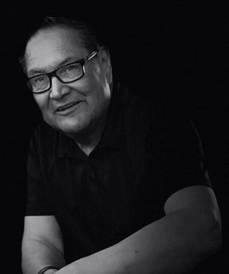 Photo: Johnathon Red Gun, a middle aged Indigenous person wearing glasses and a black short-sleeved shirt.