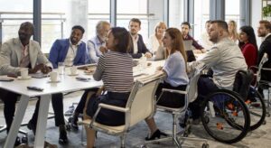 A dozen diverse workers sitting at a large table in an office.