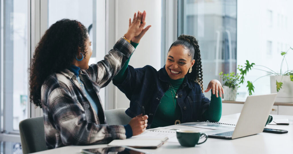 A career development practitioner and job seeker high five in celebration of an achievement.