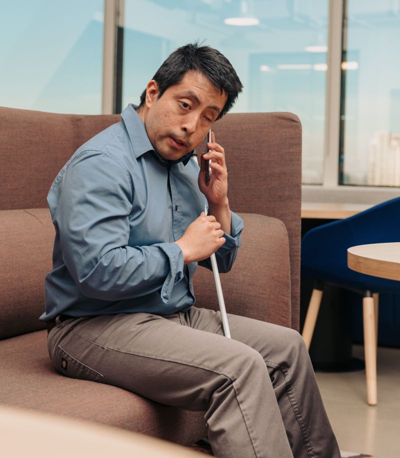 A man who uses a cane listens to his phone at work.