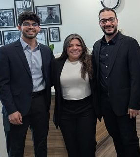 Three smiling people stand in an office