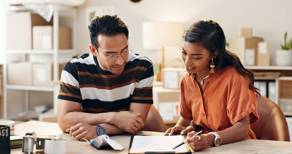 An employee and Job Coach sit at a table completing work together.
