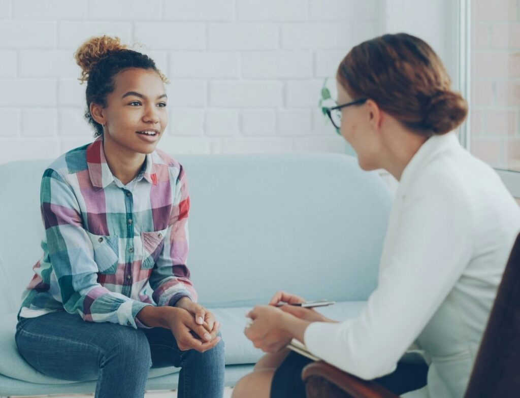 A job coach works with a young person in a workplace.