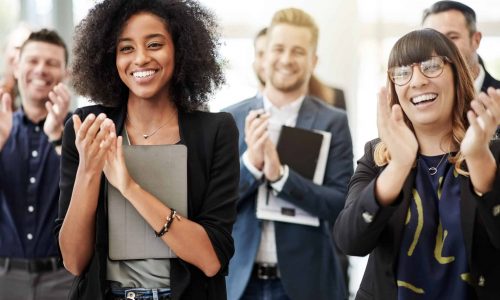 Group of people in workplace clapping and smiling.